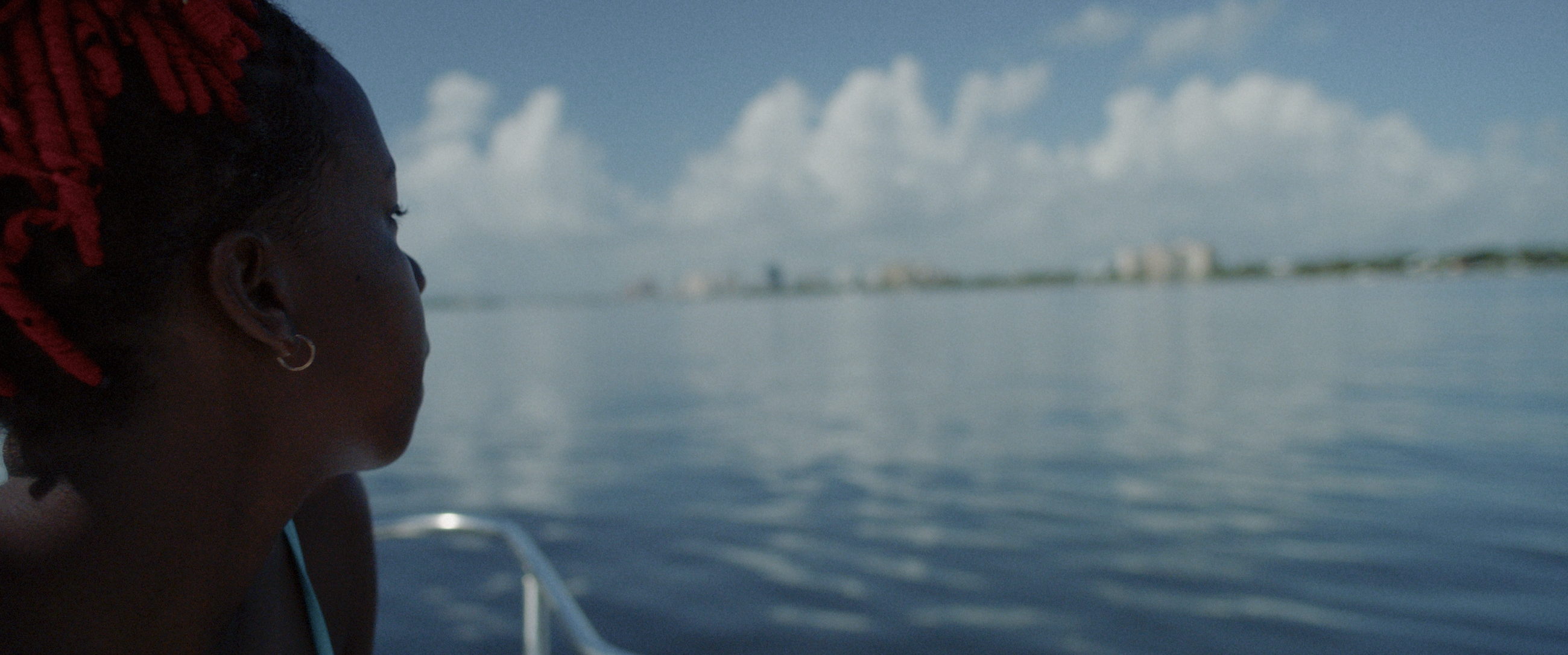 A woman looks out across open water toward a distant shoreline.