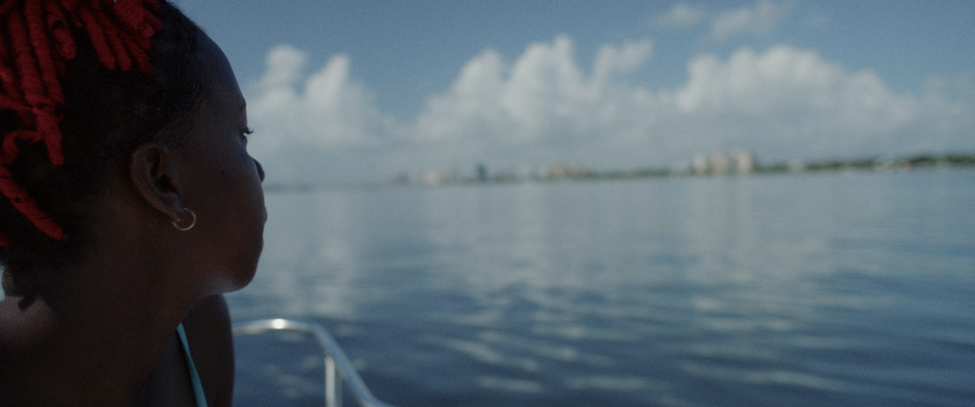 A woman looks out across open water toward a distant shoreline.