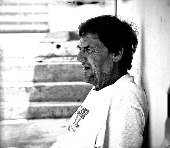 A man rests his head against a wall at the foot of a concrete stairwell.